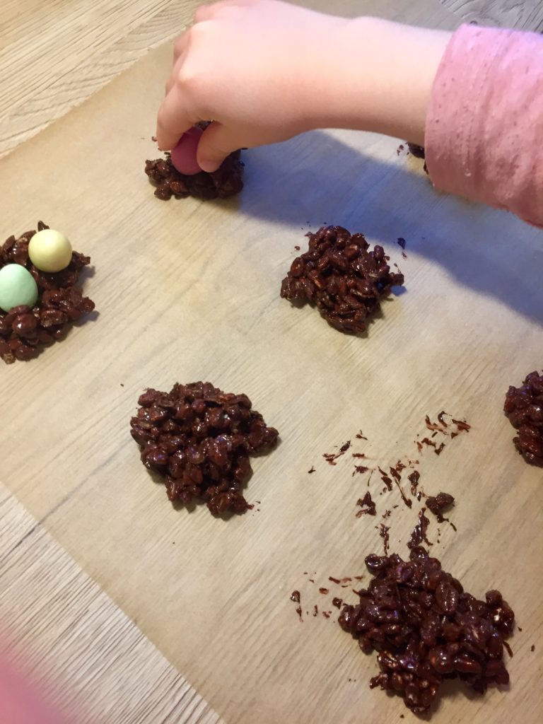 Kinder dekorieren die schokoladigen Osternester mit Schokoeiern