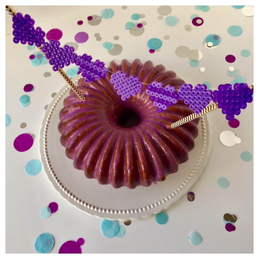 Ein Vanille-Gugelhupf mit lila Mirror Glaze und einem Caketopper aus Bügelperlen