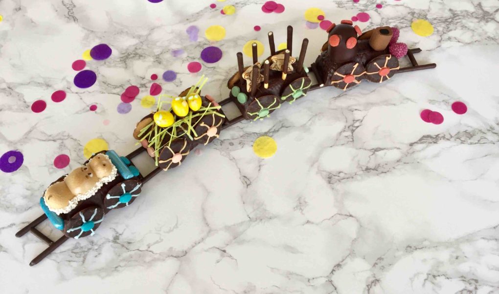 Der kunterbunte Eisenbahnkuchen für den Kindergeburtstag wird mit Süßigkeiten farbenfroh dekoriert.