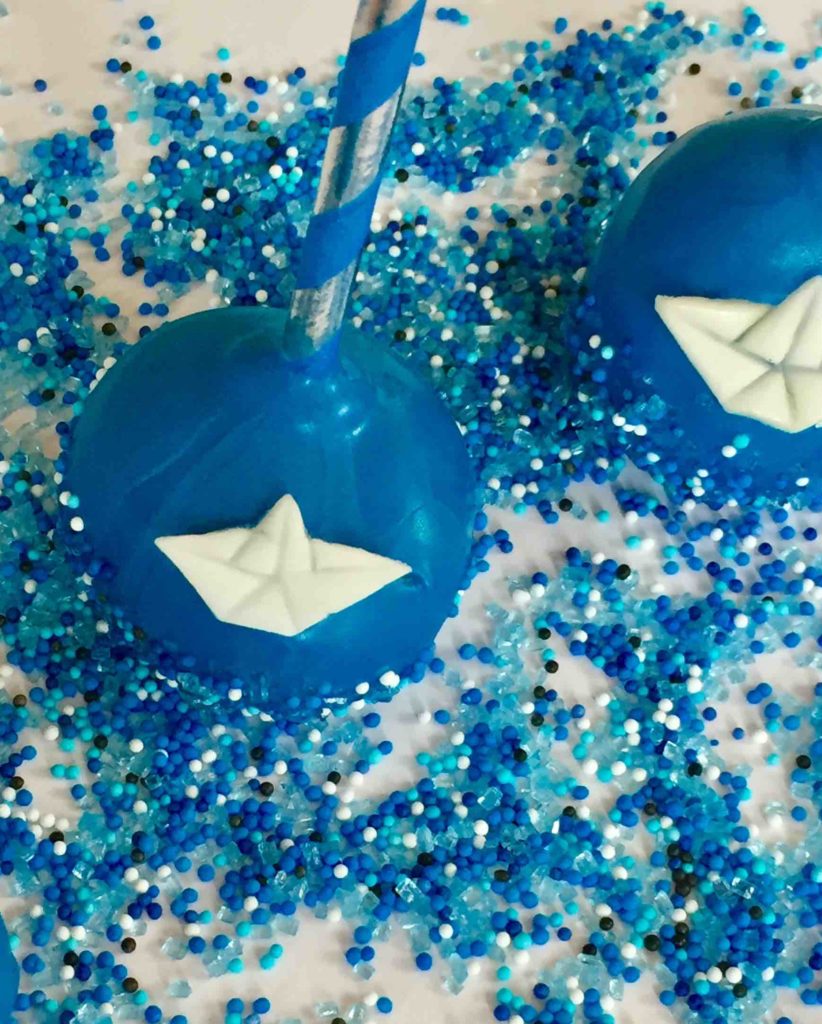 Blaue Cakepops mit Papierschiffchen aus Fondant für die maritimen Cakepops zur Taufe.