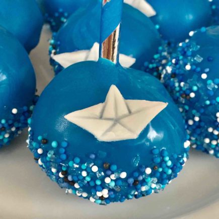 Blaue Cakepops mit Papierschiffchen aus Fondant für die maritimen Cakepops zur Taufe.
