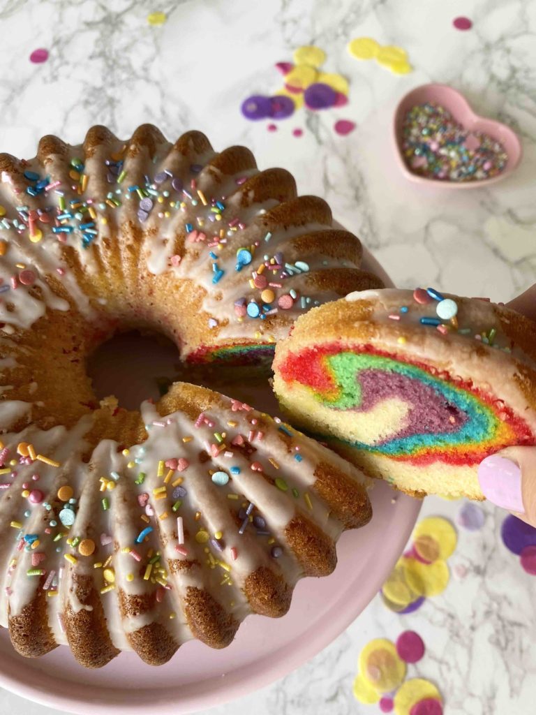 Der Surprise Cake mit verstecktem Regenbogen sieht von außen aus wie ein ganz normaler Geburtstagskuchen, dabei ist er ein kunterbunter Regenbogenkuchen.