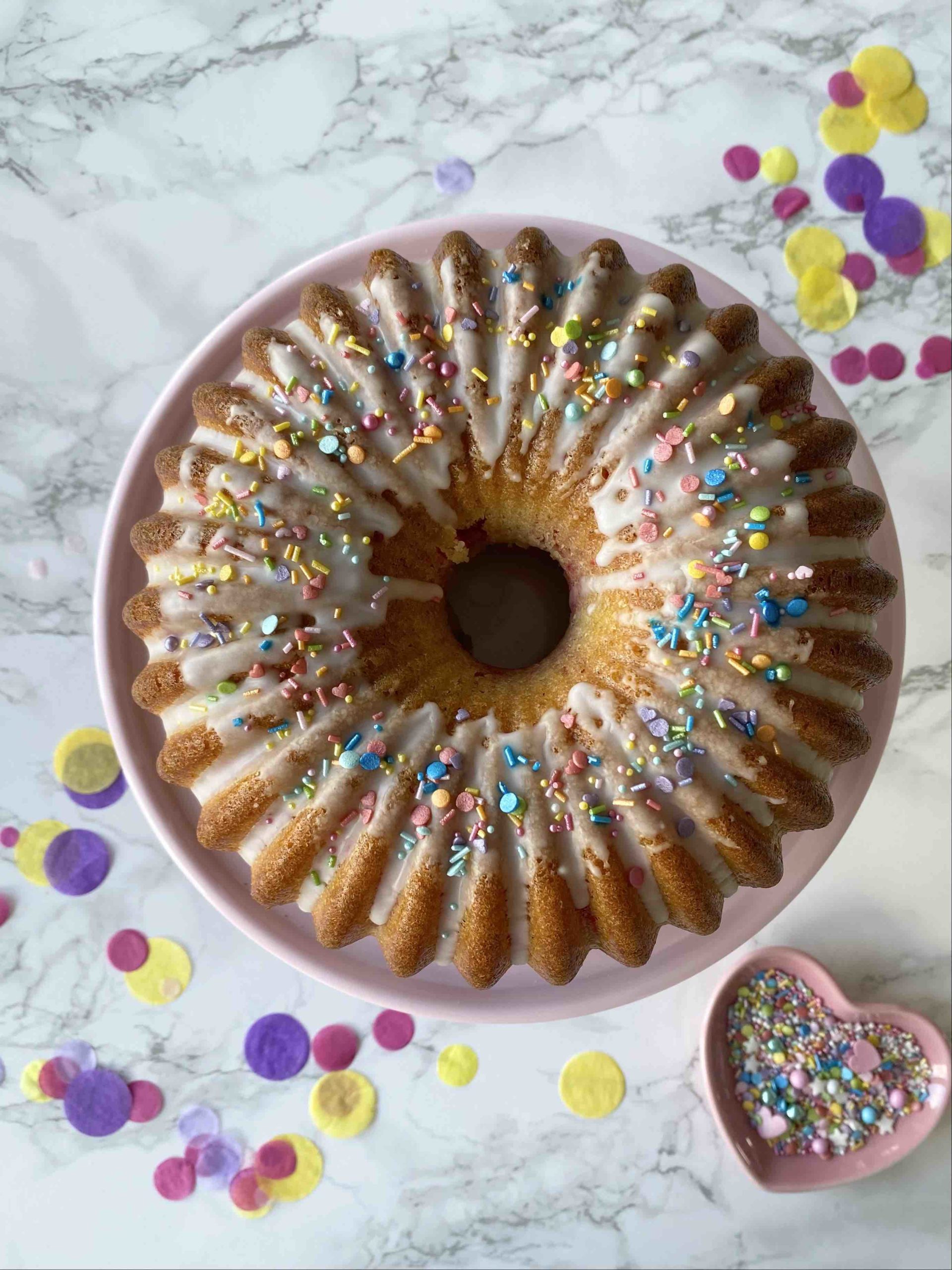 Der Surprise Cake mit verstecktem Regenbogen sieht von außen aus wie ein ganz normaler Geburtstagskuchen.
