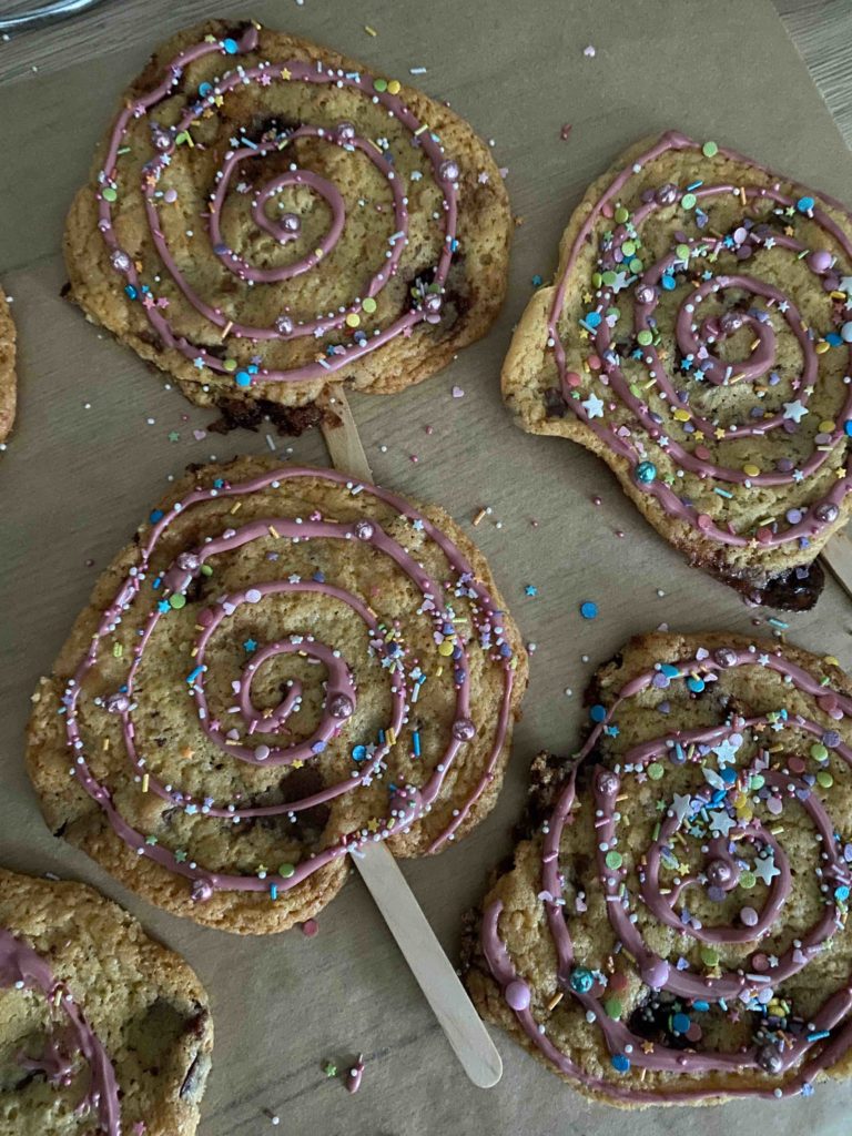 Die Cookies am Stiel werden kunterbunt als Partysnack dekoriert.